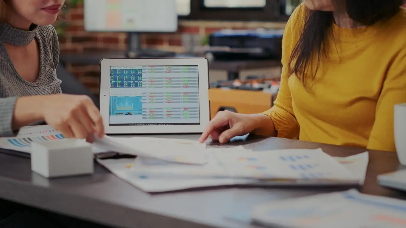 Коллеги смотрят на статистику фондового рынка на планшете, разрабатывая бизнес-проект. Женщины анализируют рост продаж и инвестиций по финансовым графикам на цифровом устройстве. Крупный план.